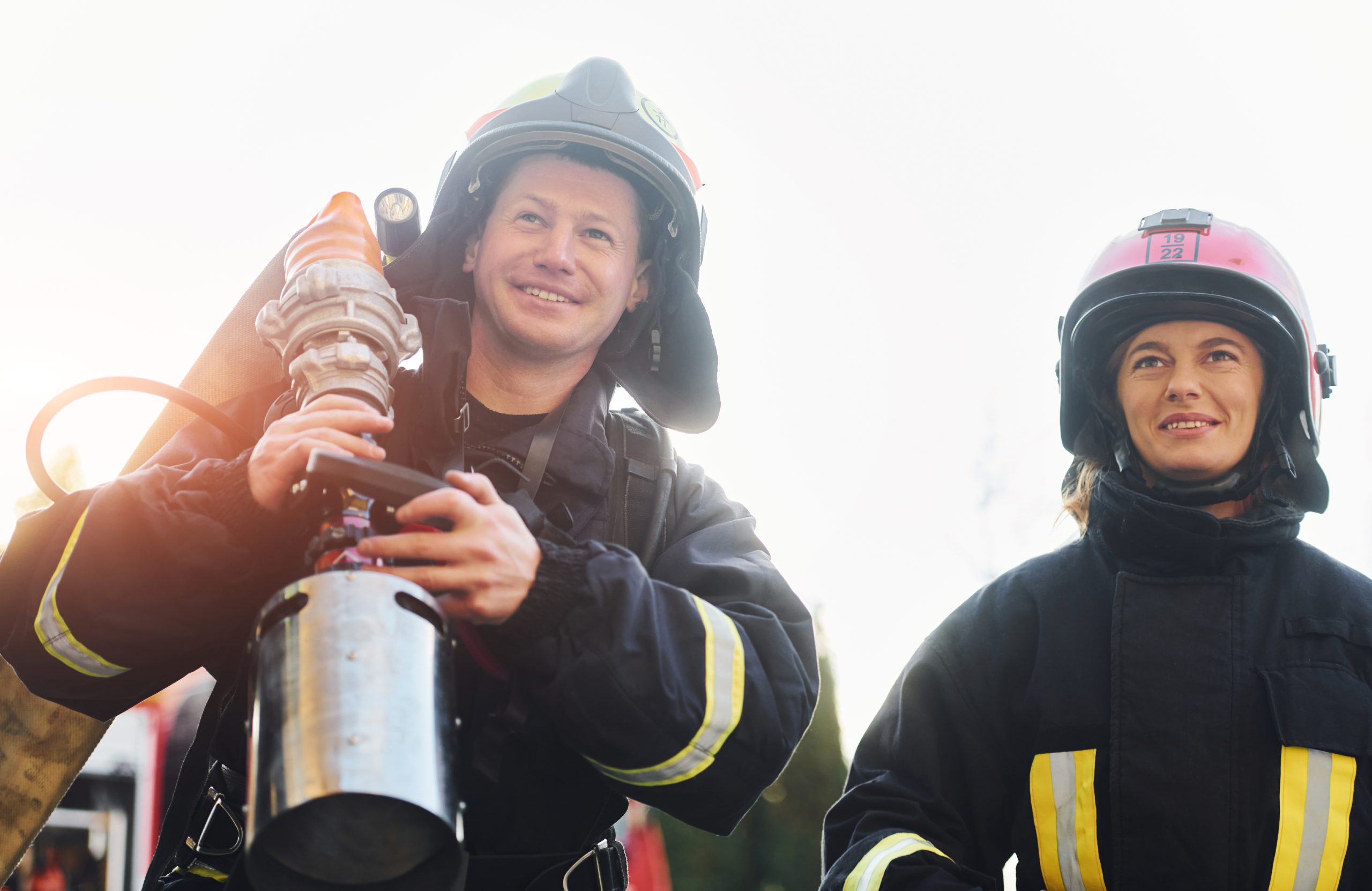 Male and female firefighters in protective uniform is outdoors together