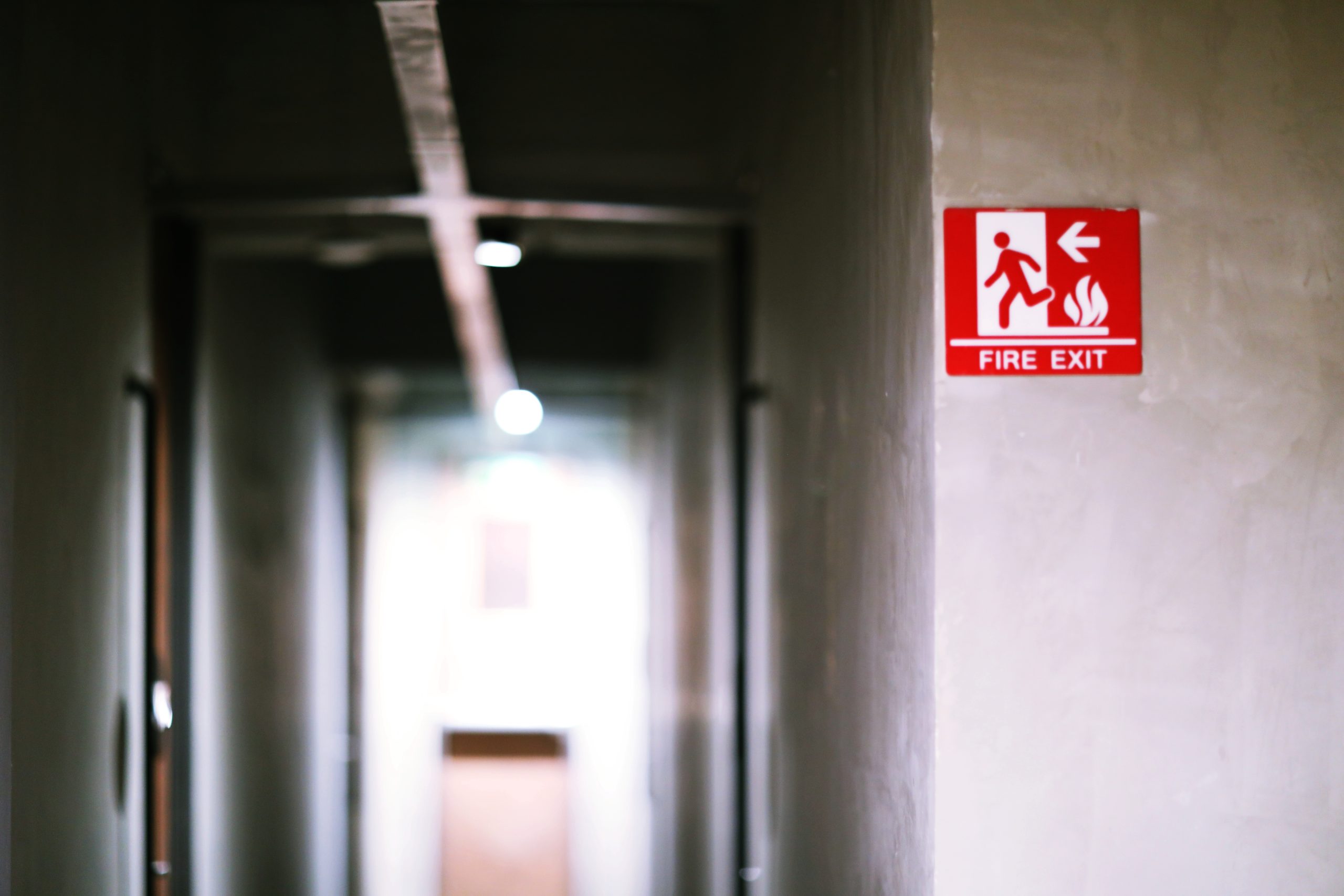 red-fire-exit-sign-on-cement-wall-indoor-building-2024-12-07-12-44-45-utc