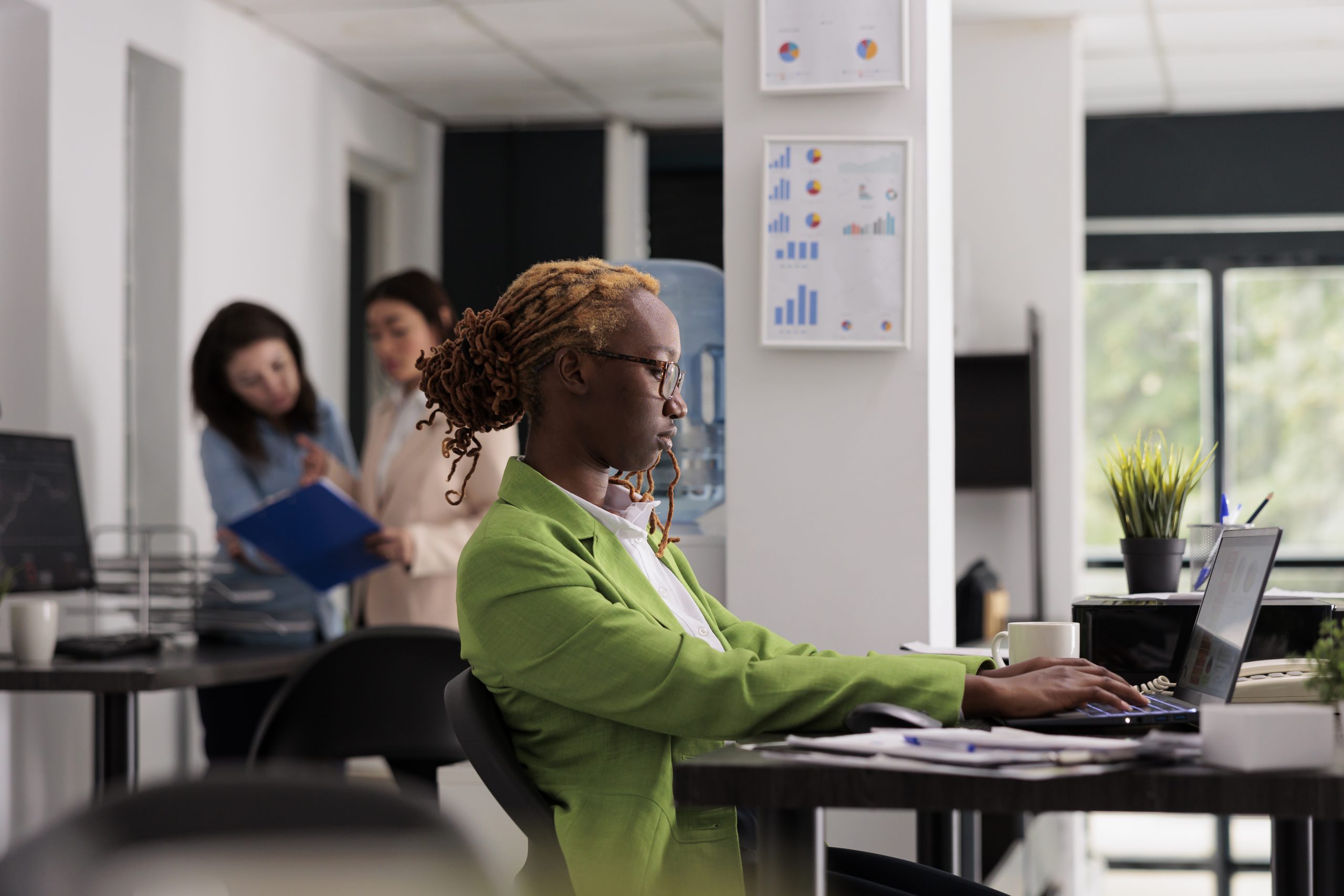 African american employee working on laptop, colleagues on background