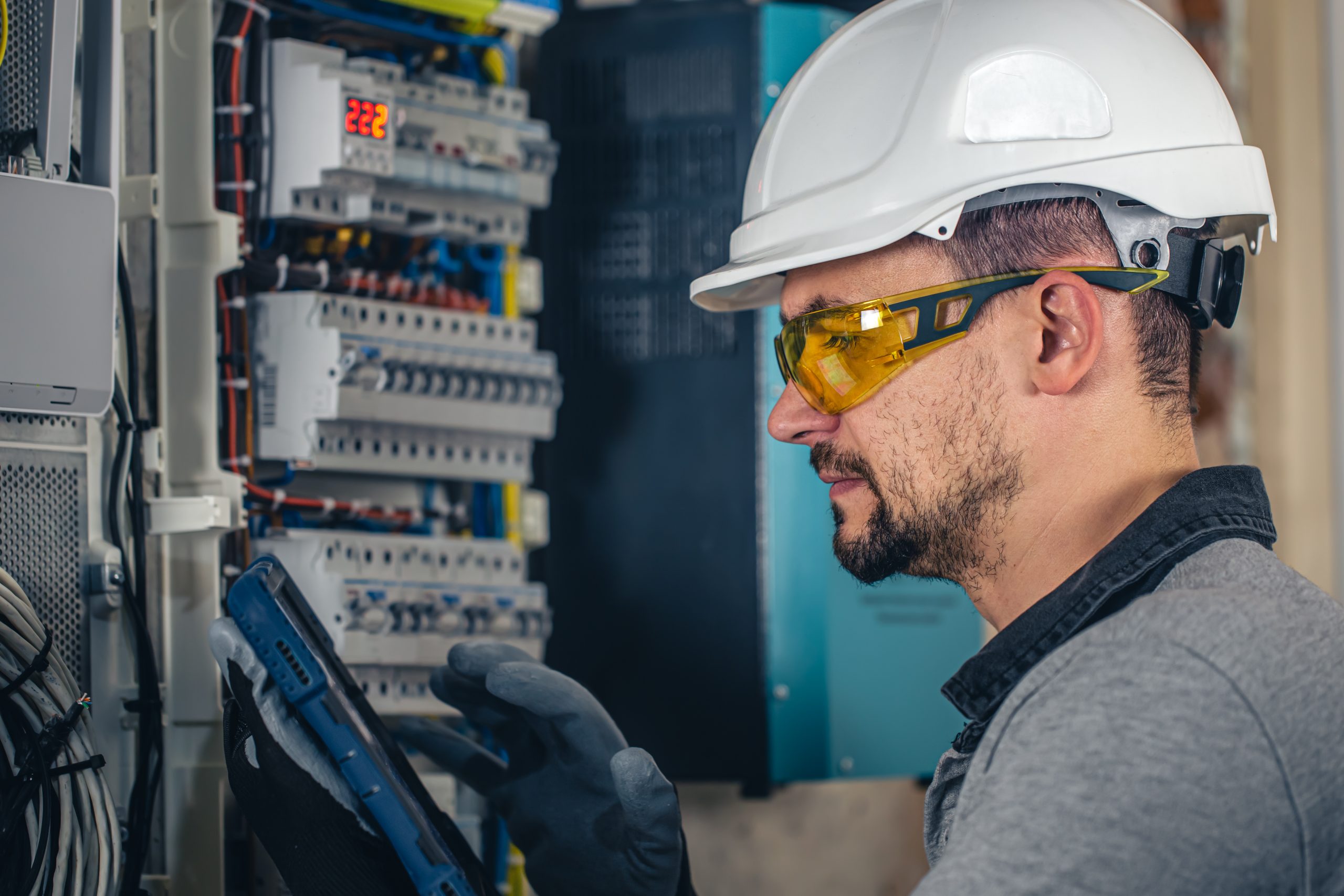 Man, an electrical technician working in a switchboard with fuses.