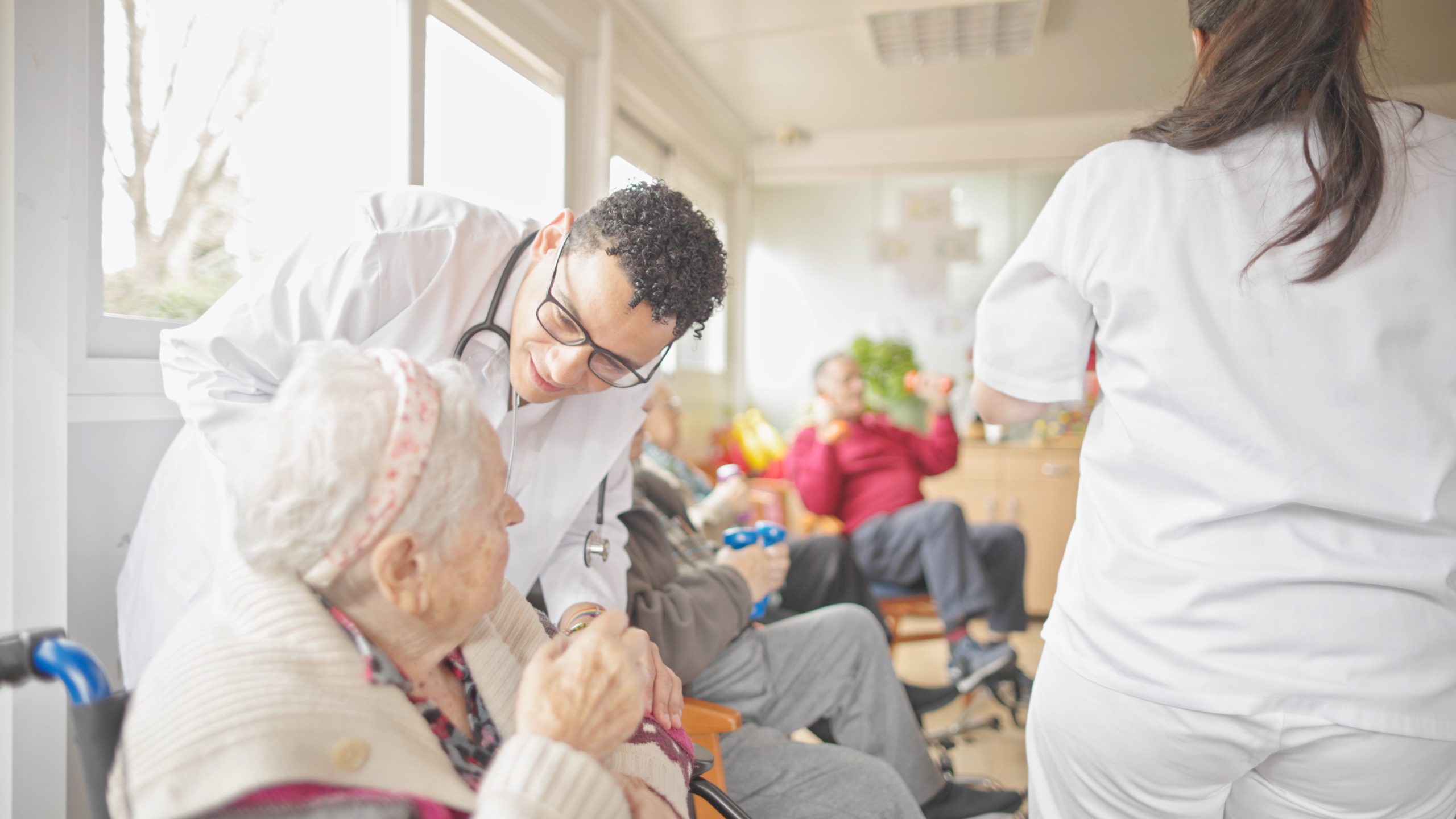 Medical staff engaging with seniors during a rehabilitation session in a bright room