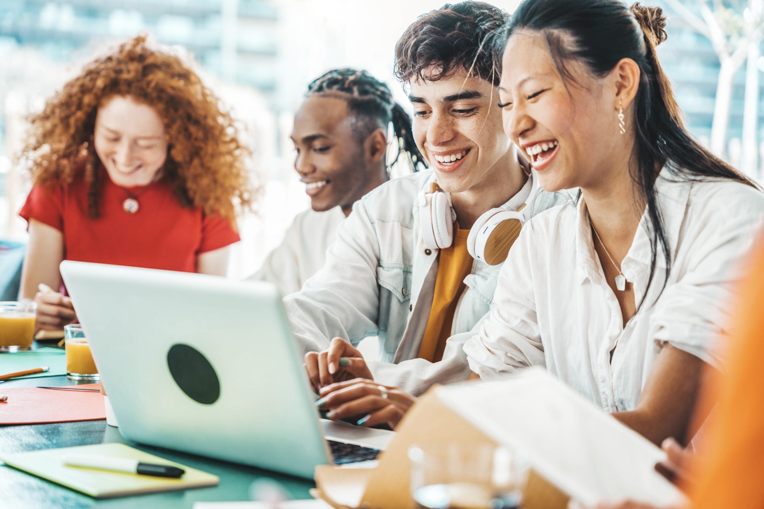 Multiracial university students sitting together at table with b